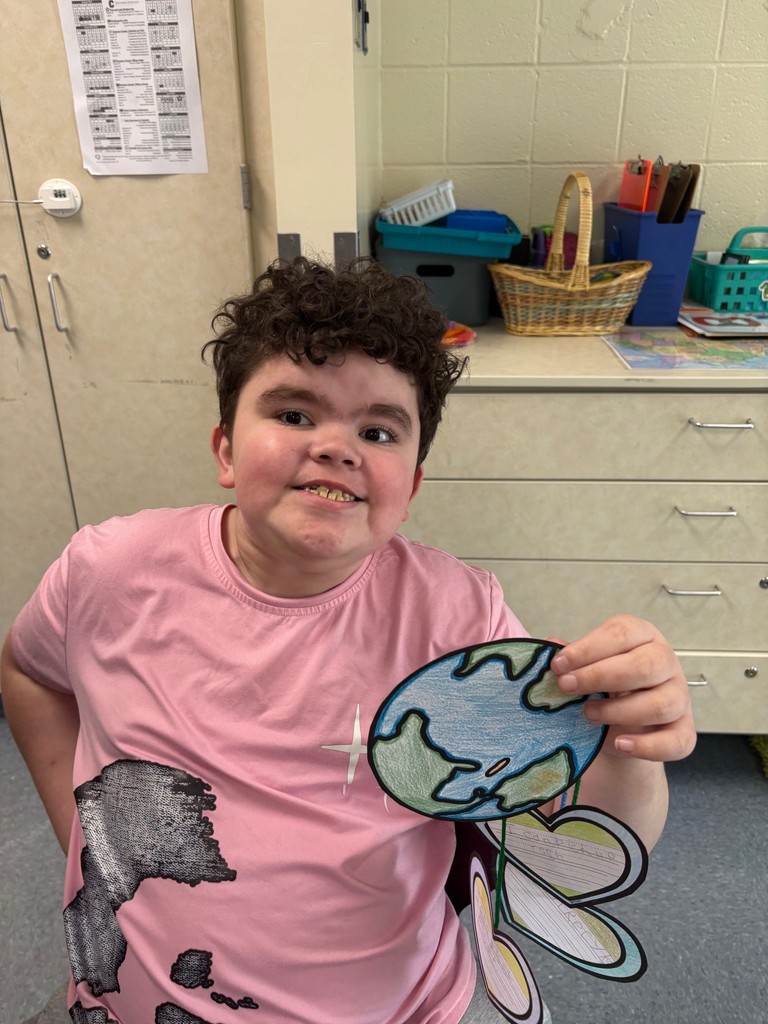 student holding an earth day project shaped like the earth