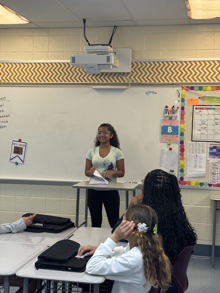 Student standing in the front of the class smiling
