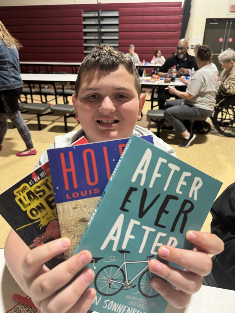 student holding books they won