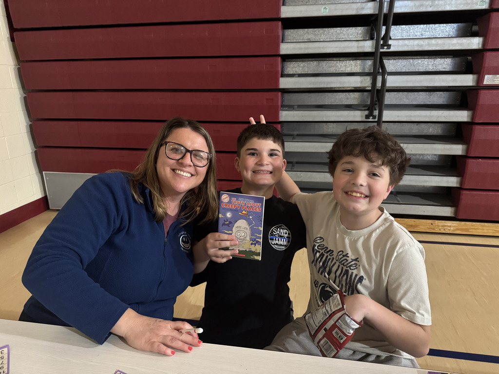 students and parents sitting together smiling with books they won