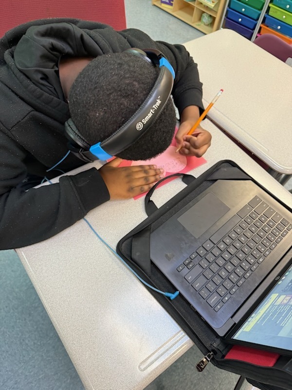 boy writing a kindness card on a heart shapped card