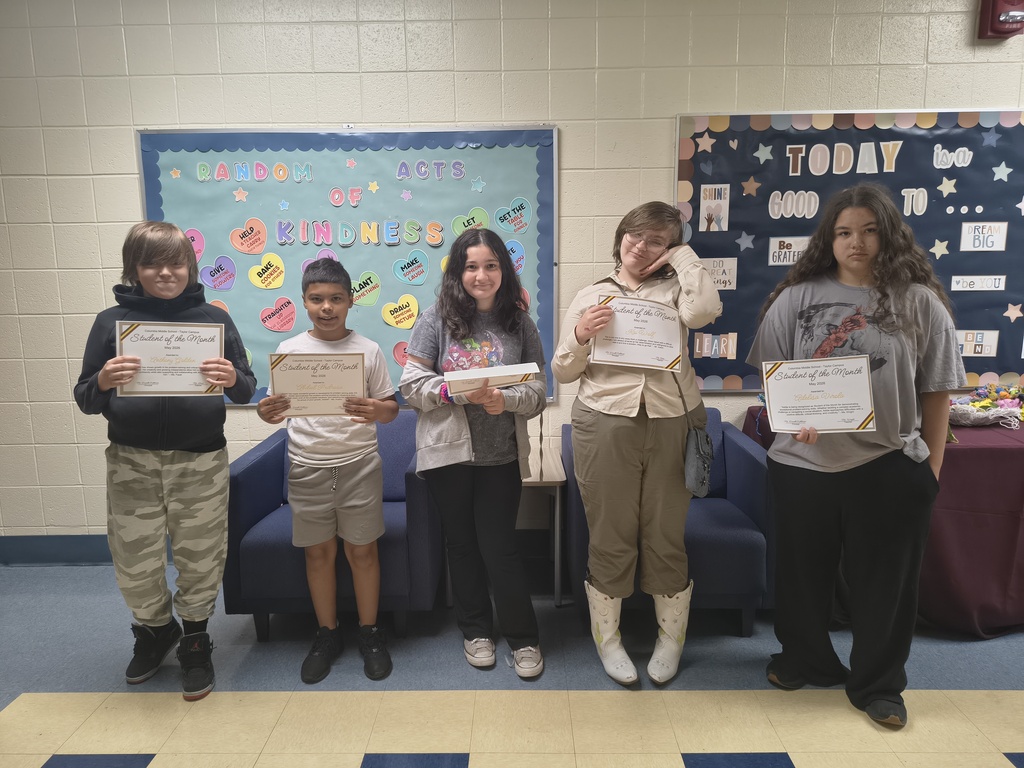 Five students proudly pose with their “Student of the Month” certificates at Columbia Middle School – Taylor Campus. The students are standing in front of colorful bulletin boards that read “Random Acts of Kindness” and “Today is a Good Day To…” while celebrating their achievements for the month of May.