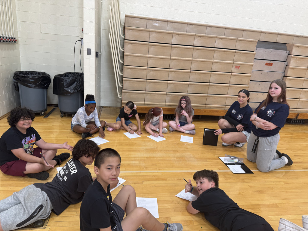 students sitting in a circle with papers and pencils