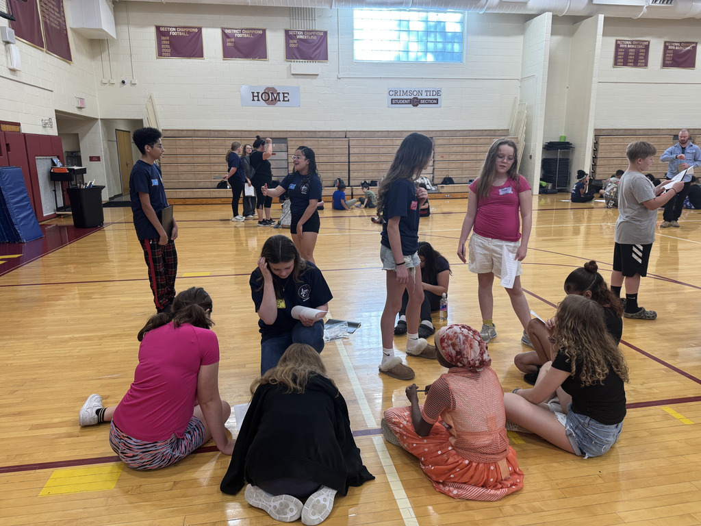 students sitting and standing at the gym