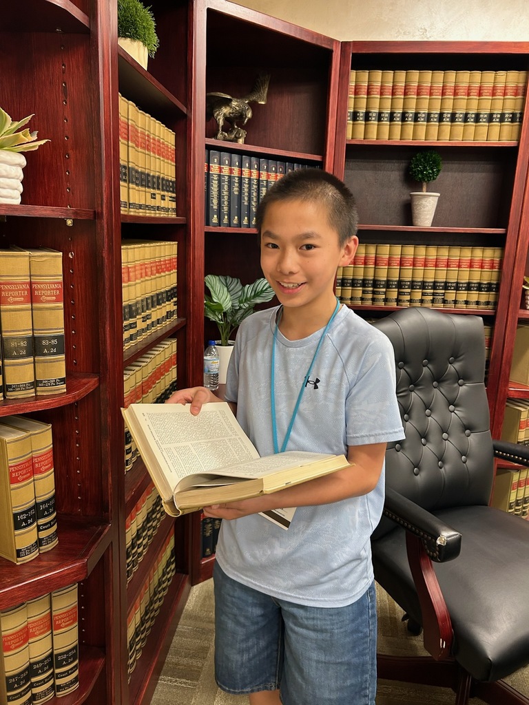 A student holding a book standing in an office space. 