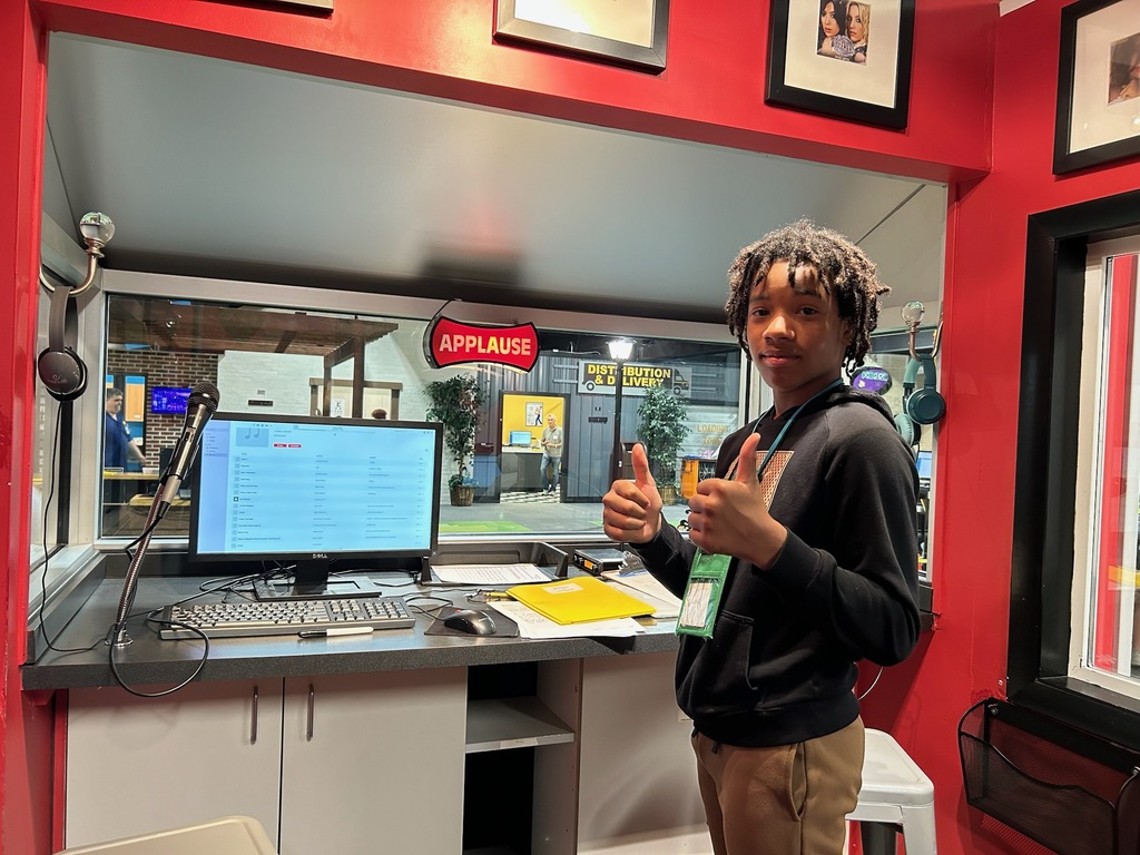 Student standing in front of a computer system smiling giving the tumbs up 