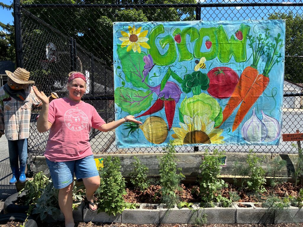 lady standing in front of a sign that says 'grow' with vegetables painted on it 