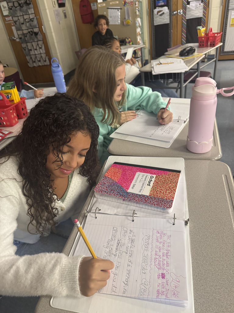 5th grade students work on personal narrative writing at their desks, focusing on a specific moment and adding details to bring their stories to life.