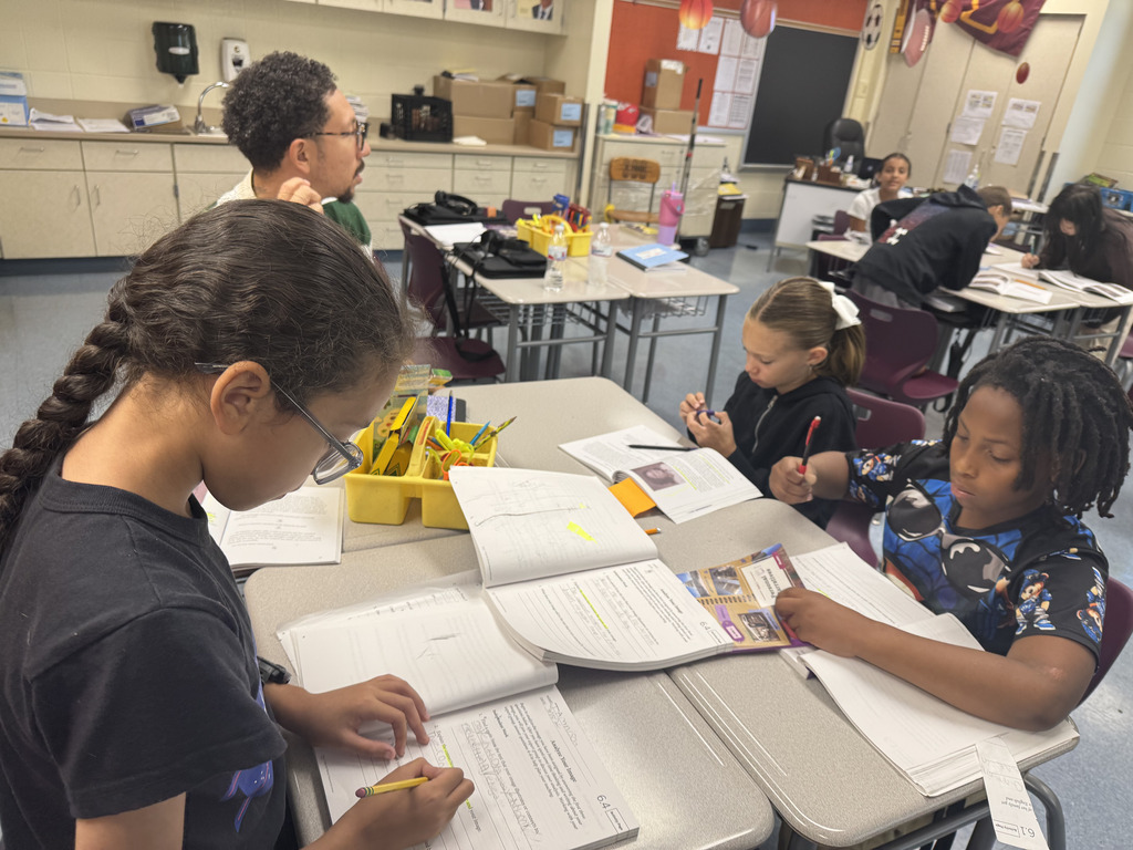 students sitting at tables working on their books