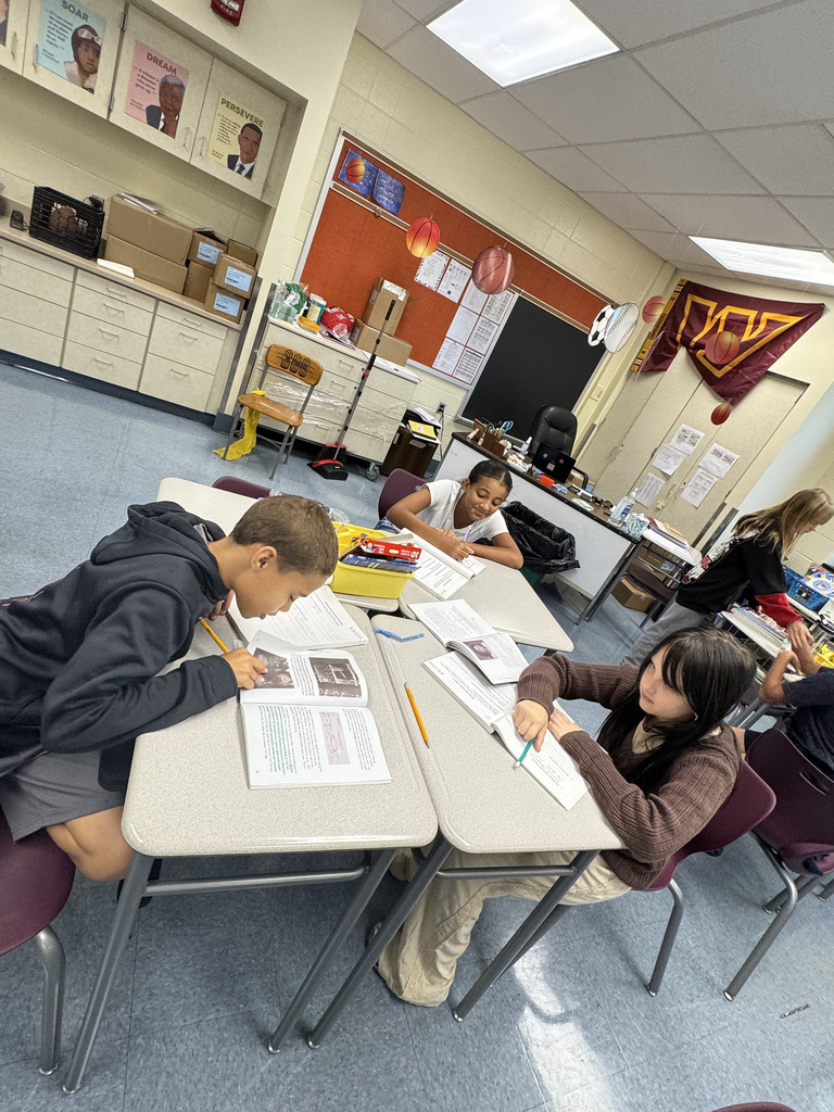 students sitting at tables working on their books