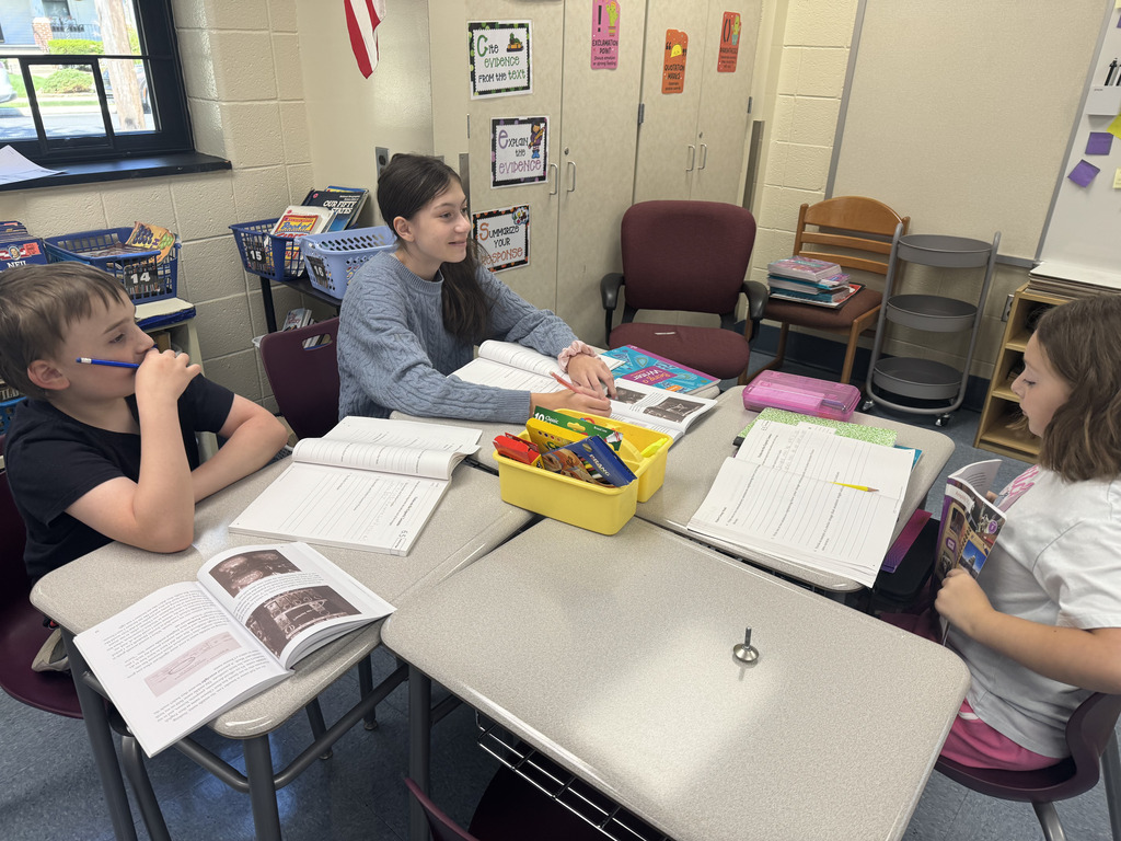 students sitting at tables working on their books