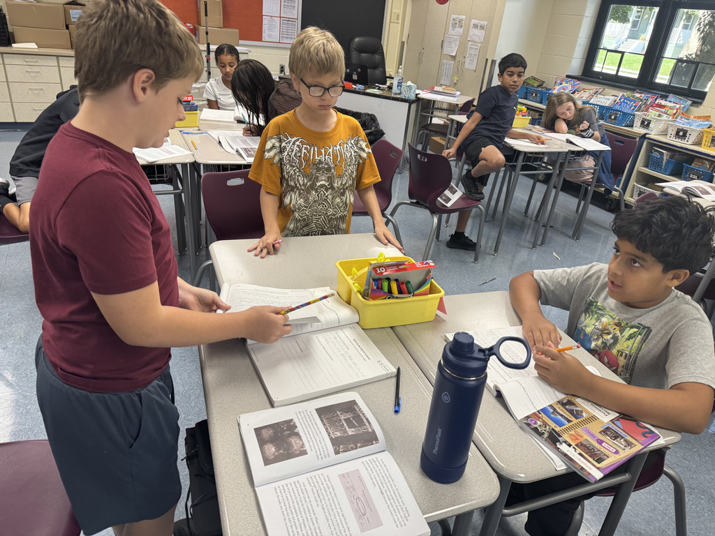 students sitting at tables working on their books