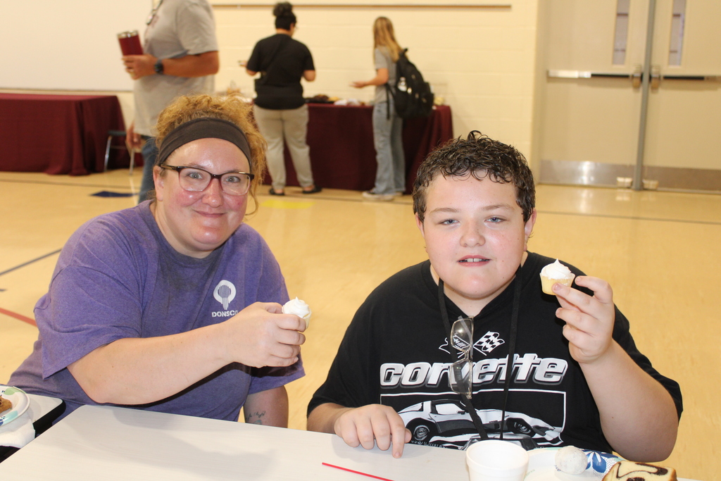 parent and student sitting together smiling with cupcakes
