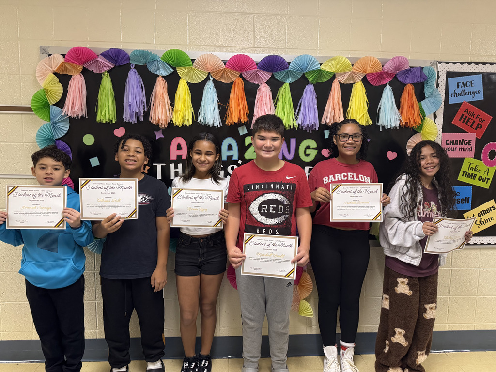 Six Columbia Middle School - Taylor Campus students stand together in front of a colorful “Amazing Things” bulletin board, each holding a framed Student of the Month certificate for September 2026. The students are smiling and posing for a group photo. The display behind them features colorful paper fans, tassels, hearts, stars, and positive messages about facing challenges, asking for help, changing your mind, taking a timeout, and believing in yourself.