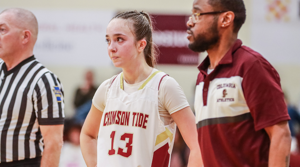 A Crimson Tide girls basketball player wearing number 13 stands beside coach Keyes and referee during a game.