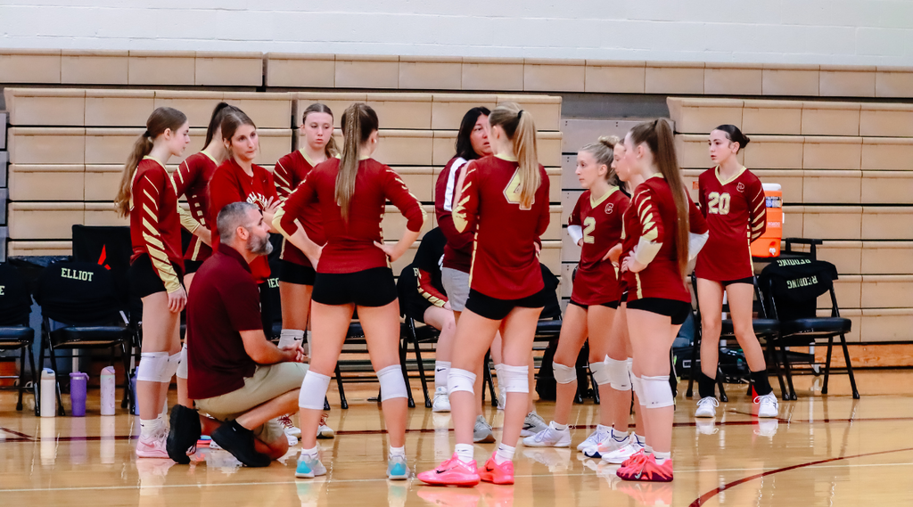 - CHS girls volleyball team gathers around  as coach mccarty is kneeling during a timeout in the gymnasium.