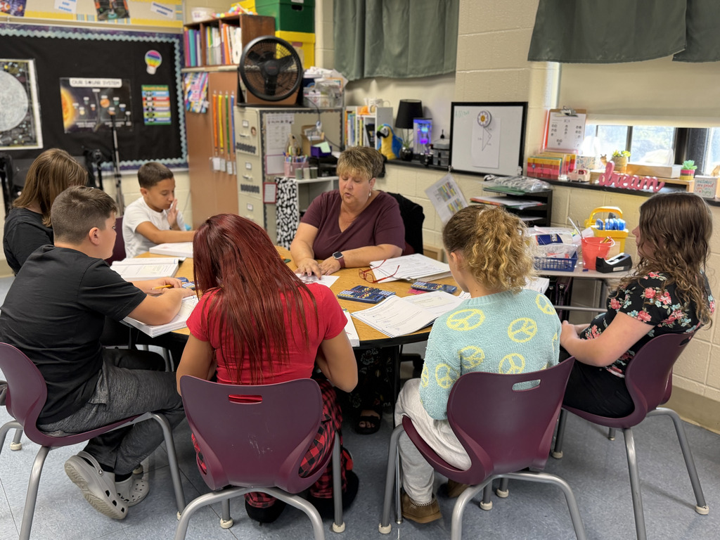 students sitting at tables engaged with the teacher