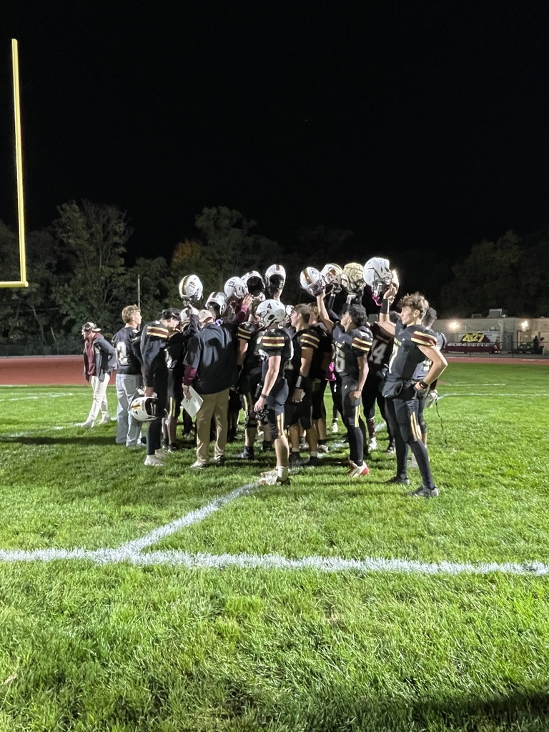 Columbia Crimson Tide football players raise their helmets in celebration on the field following a nighttime victory.