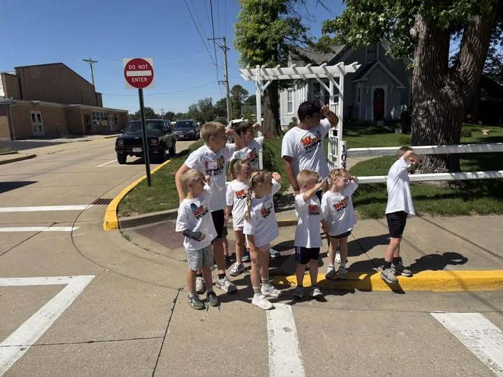 group of kids standing on sidewalk looking down the road