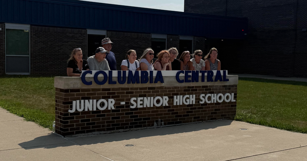 Picture of ten classmates behind the junior - senior high sign
