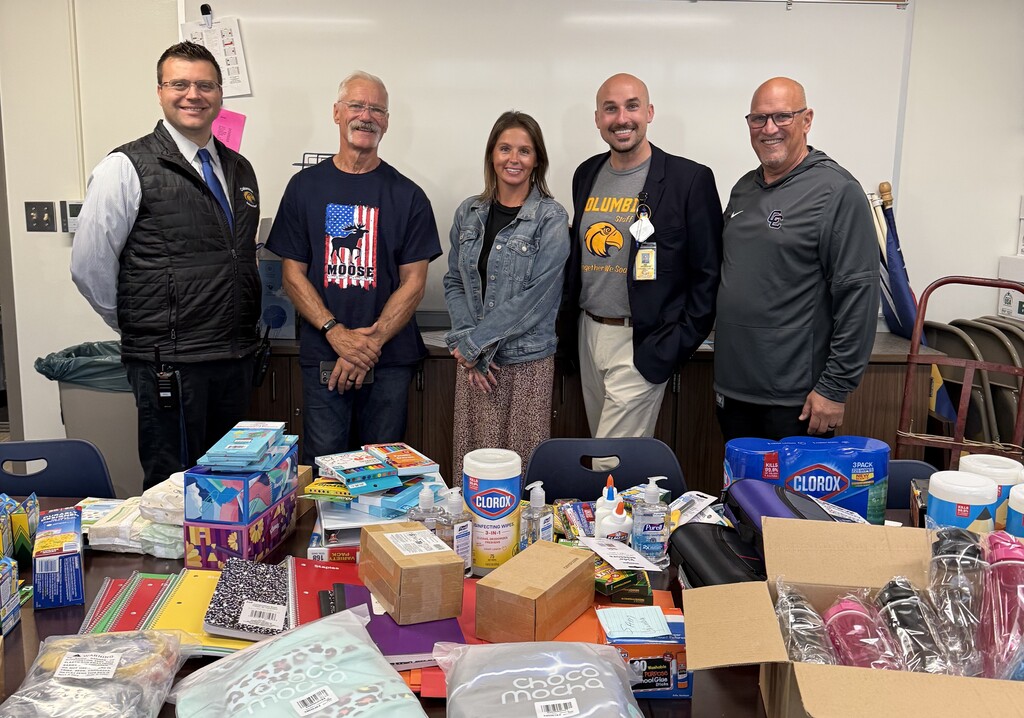 A member of the Moose Lodge with school supplies they donated and the elementary principals.