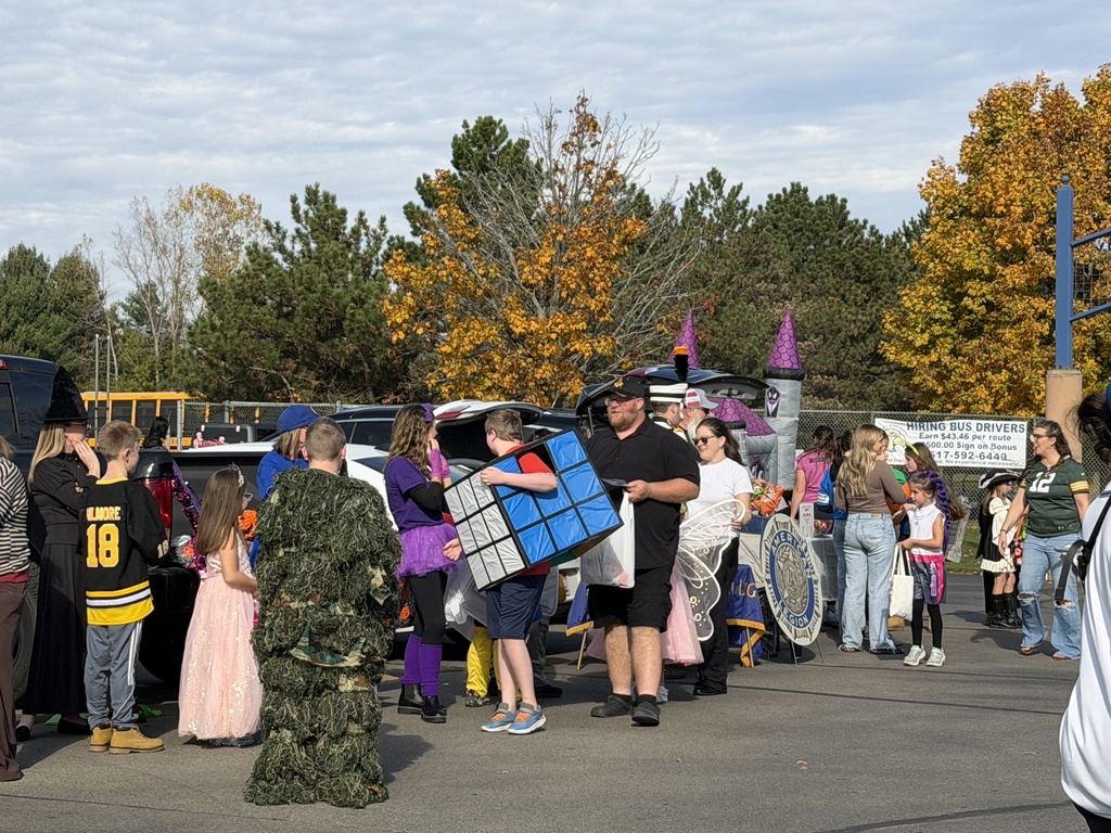 A line of costumed students getting candy at trunks