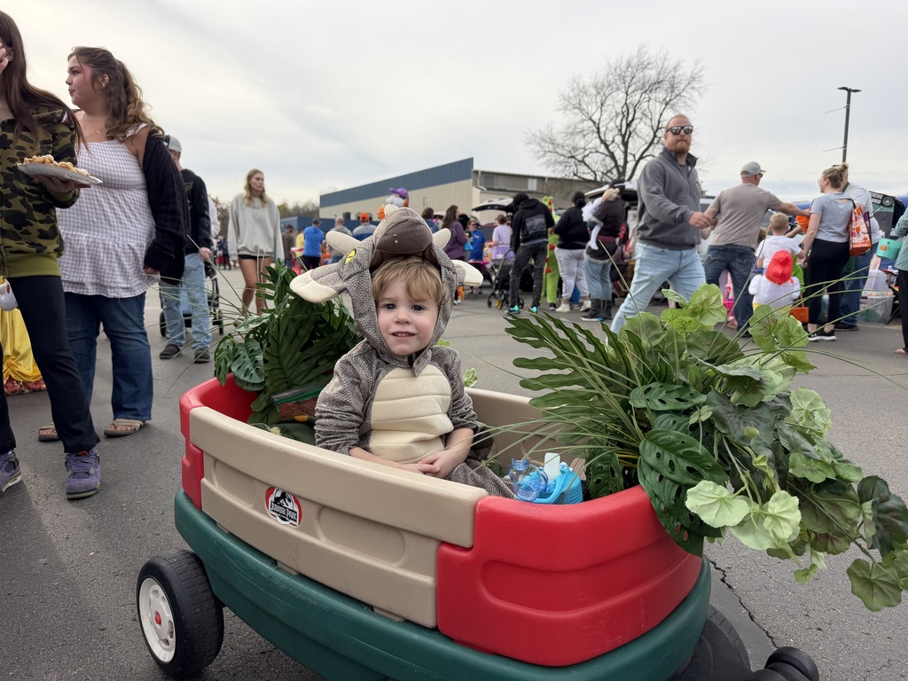 Kid in triceratops costume in a Jurassic park decorated wagon