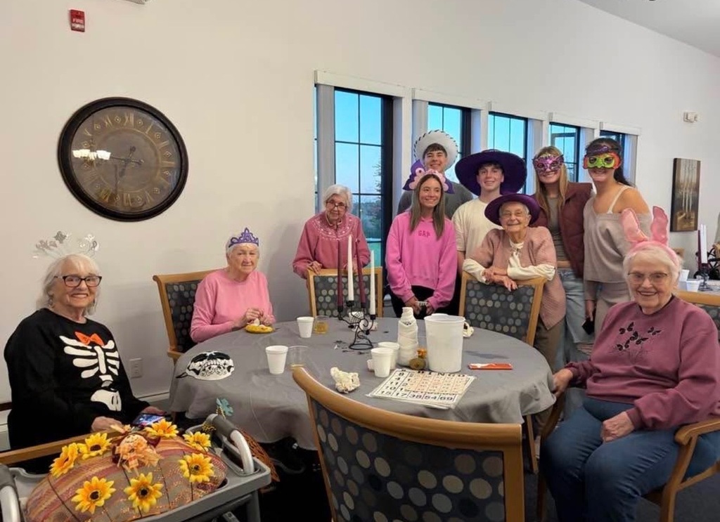 Seniors at a table and students standing behind them