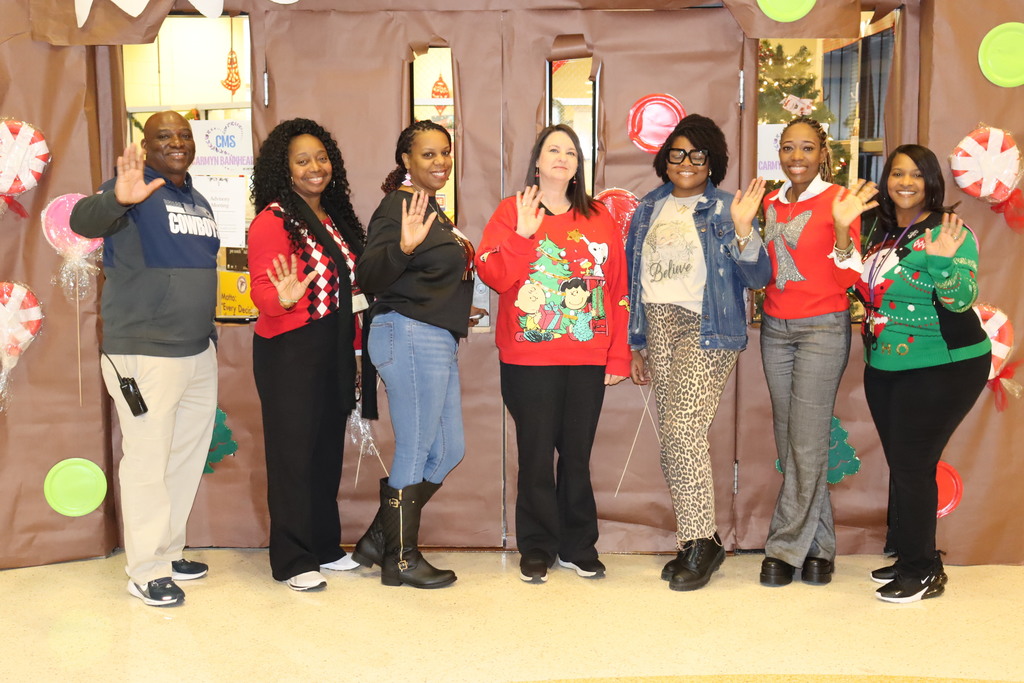 CMS staff waive while wearing their holiday sweaters. 