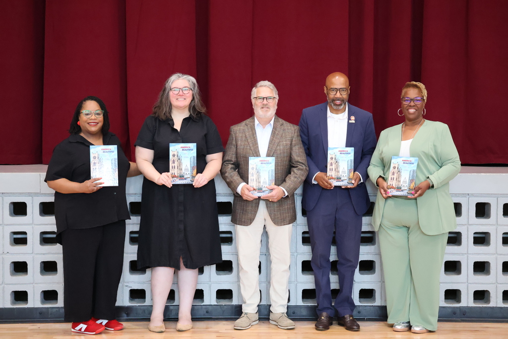 City and school officials pose with Friendly City Books with a book donation for Earth Day.
