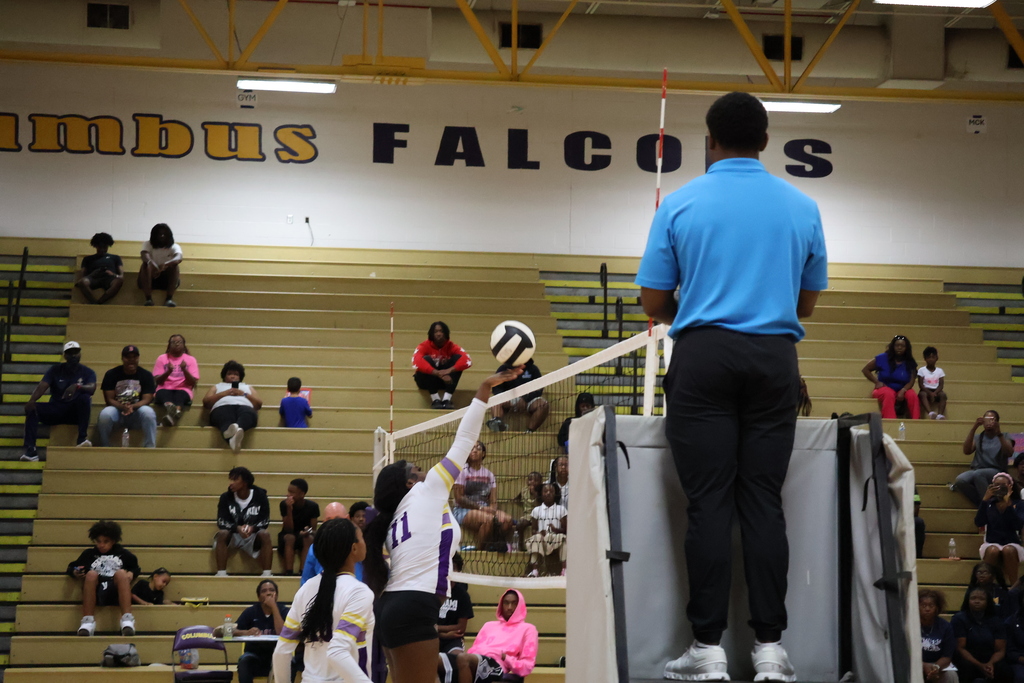Columbus High volleyball player hits the ball over the net.