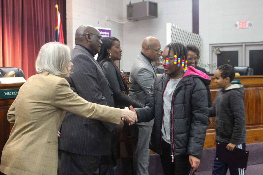 Board member congratulates student and shakes hand