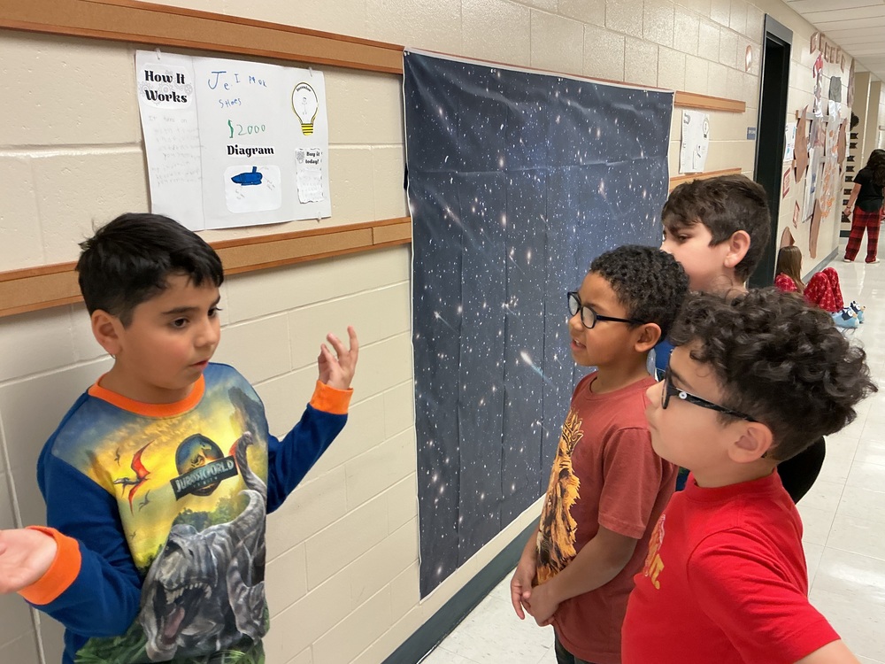 Student explaining his invention to peers.