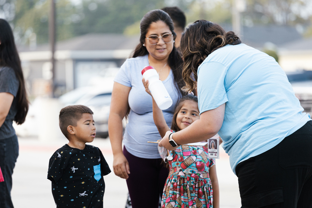 A North Park kindergarnter shows a teacher a water bottle as her mom and brother watch. It was the first day of school at North Park.