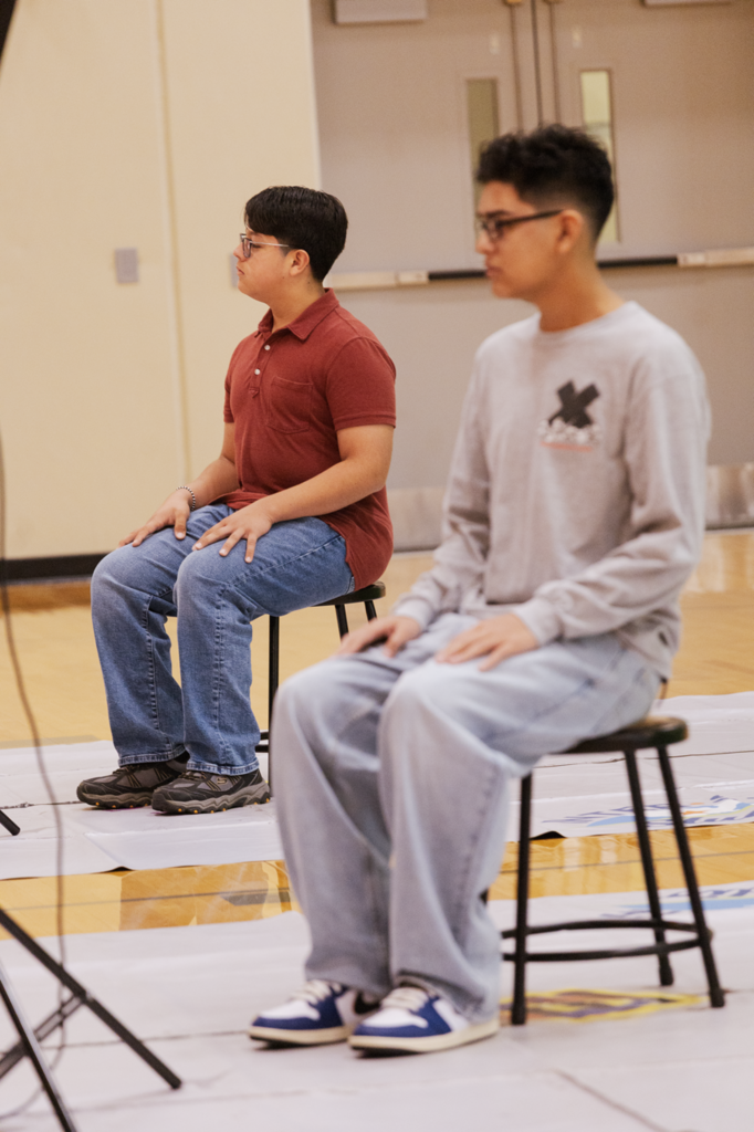 Two CHS freshmen prepare for their student pictures. They are sitting on a stool with flashes off camera.