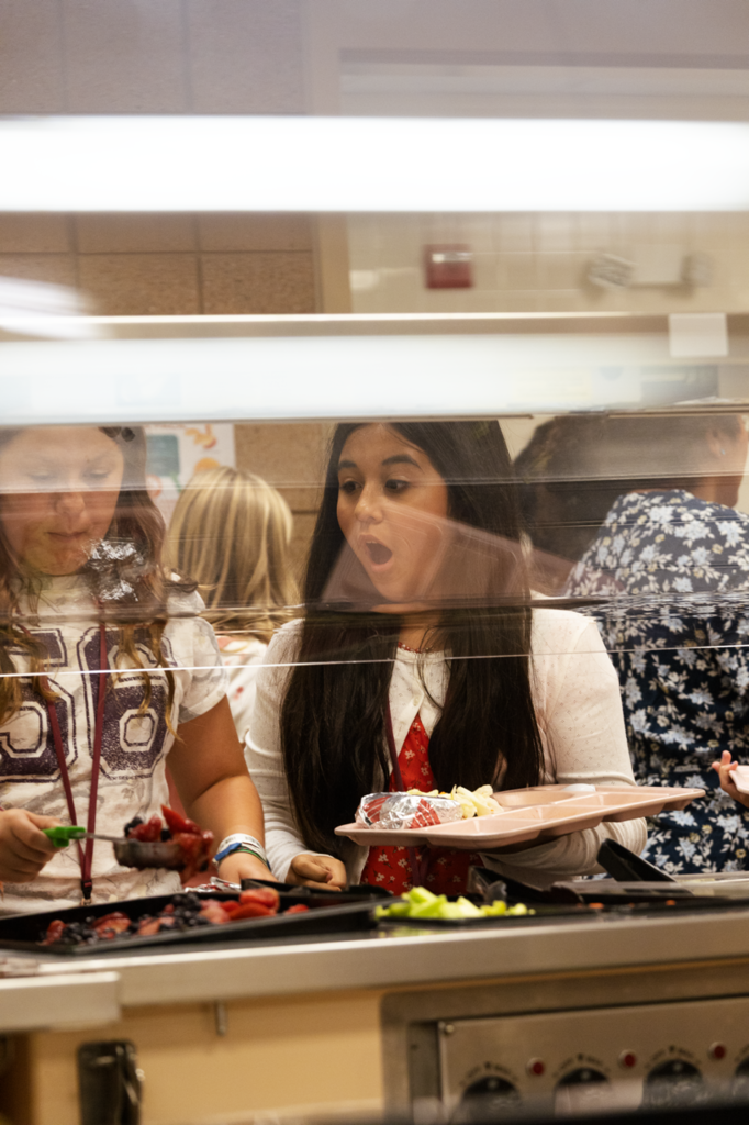 A CMS 5th-grader reacts to a lunch menu item with a surprise look,  as she holds a tray in line.