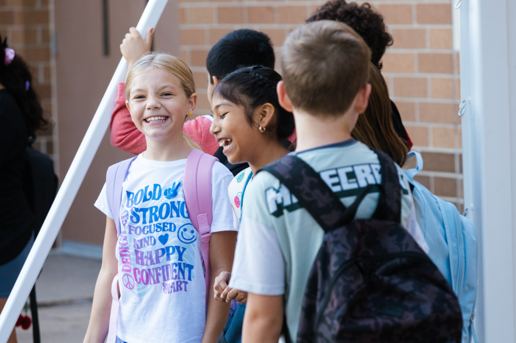A pair of Emerson fourth-grade girls grin big while waiting in line before the first day of school in 2025.