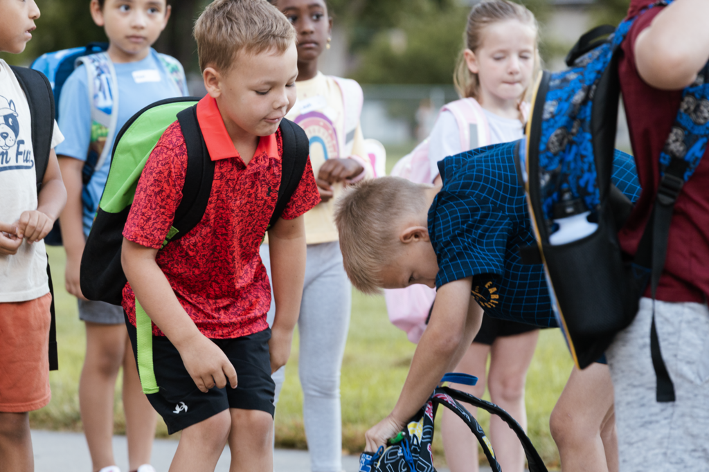 Two Emerson boys dig into  a backpack while in the line for the first day of first grade in 2025.