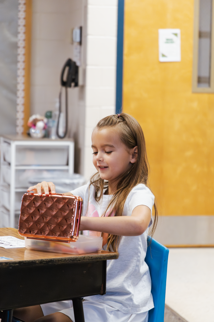 A second-grader in Ms. Grossnicklaus grabs a colored pencil from a pencil box during class.