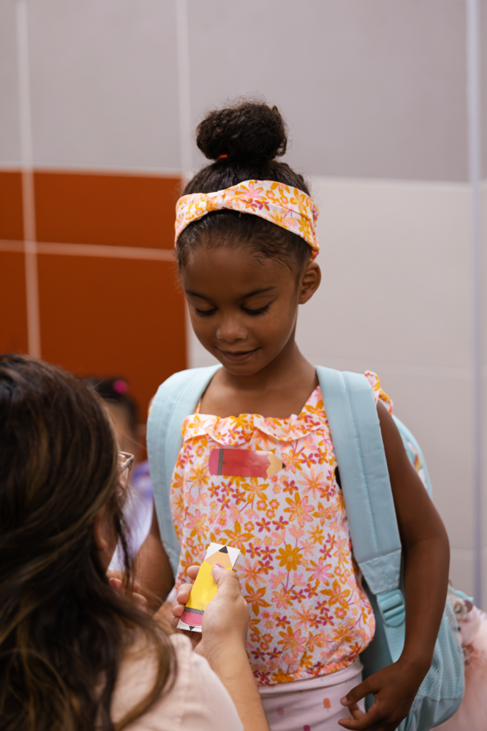 A teacher at Kramer preschool places a nametag on a student prior to her first day.