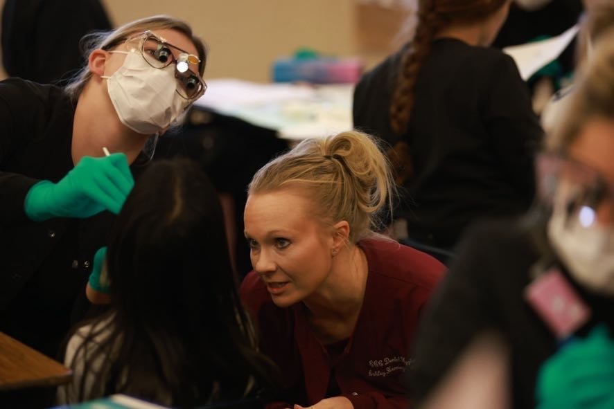 Dr. and student examining an elementary student's teeth