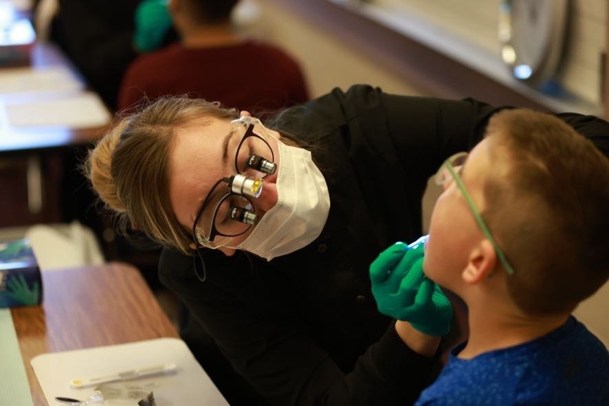 Dental hygienist student performing exam on male student