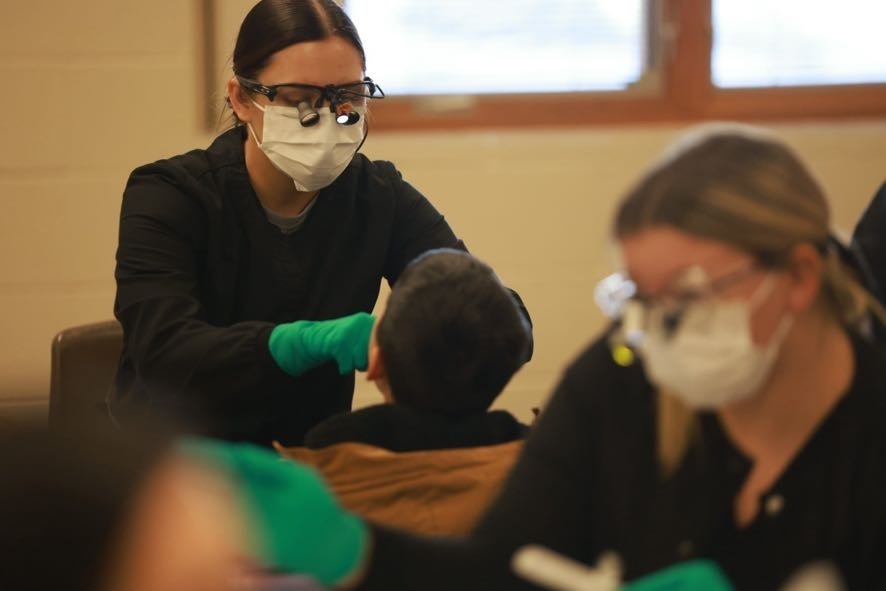 Dental hygienist student performing exam on male student