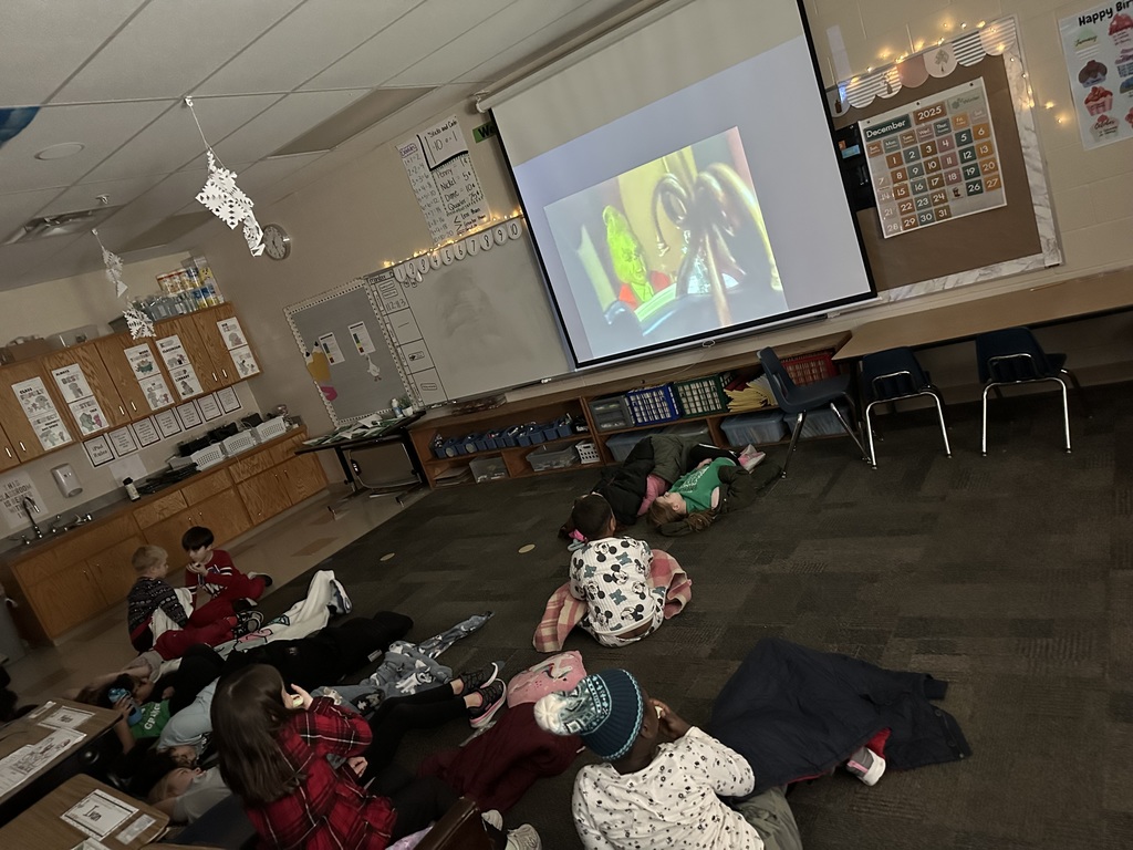 students in pajamas sit on the floor while a movie is projected