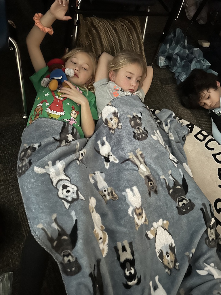 students lie on the floor under a blanket