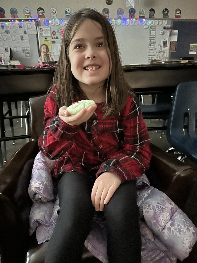 a student holds a cookie that is green with red