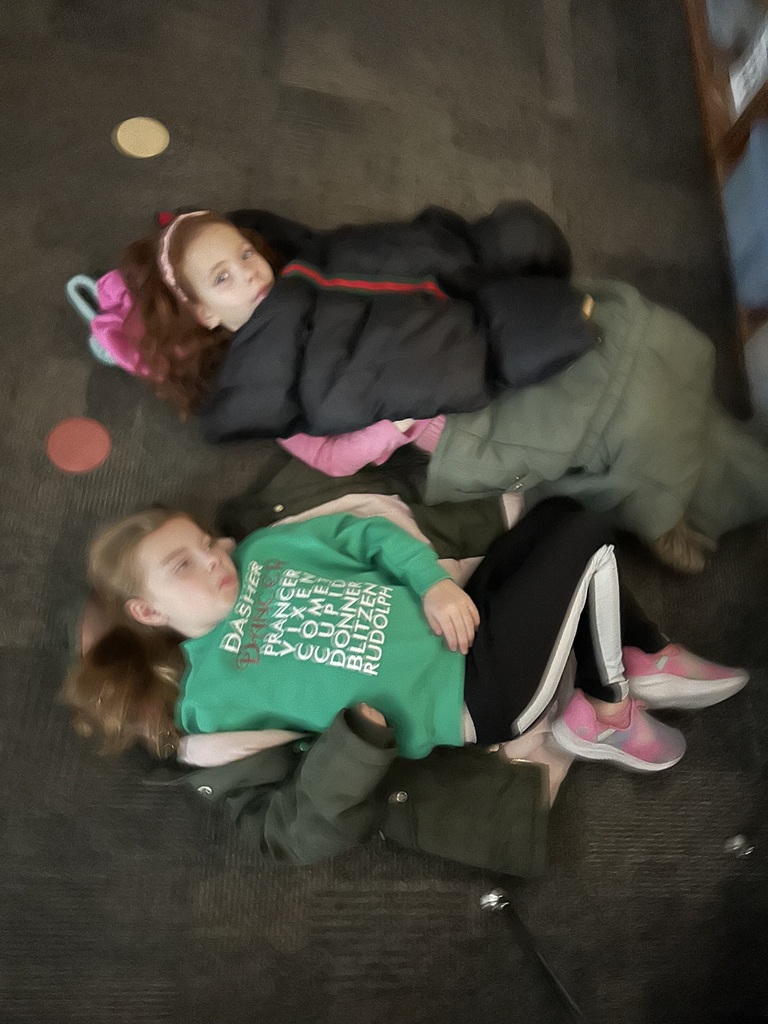 two students lie on the floor wearing coats