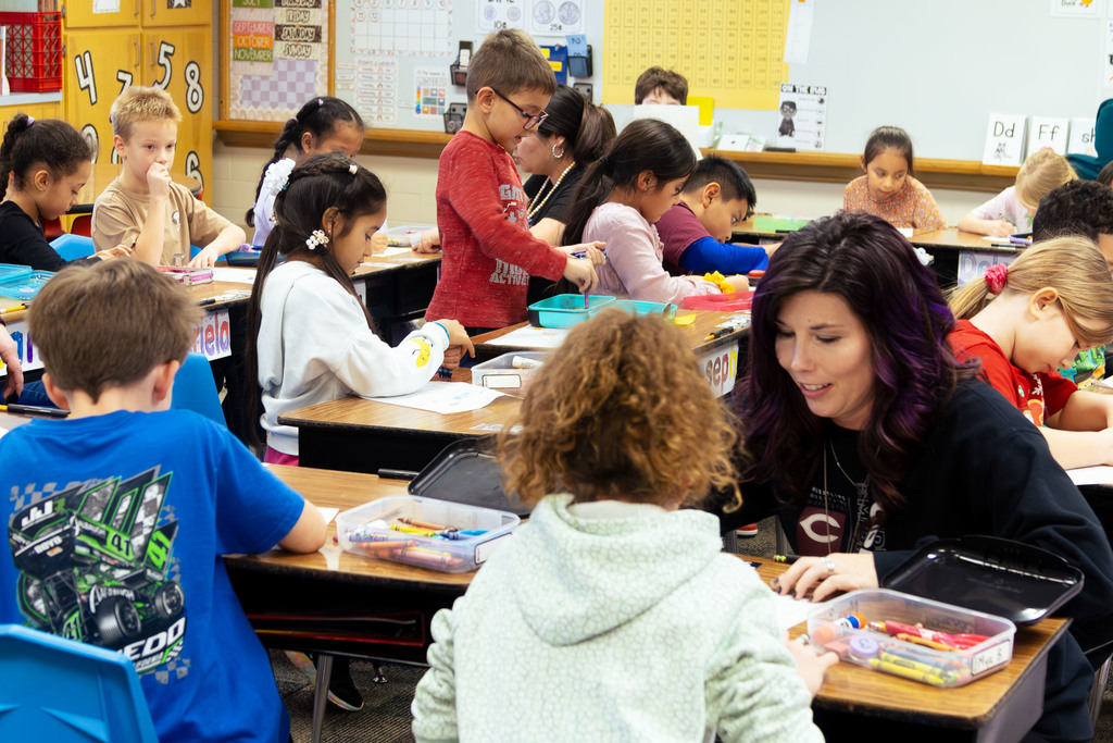 students learning in the classroom.  teacher and paraeducator shown working with individual students.