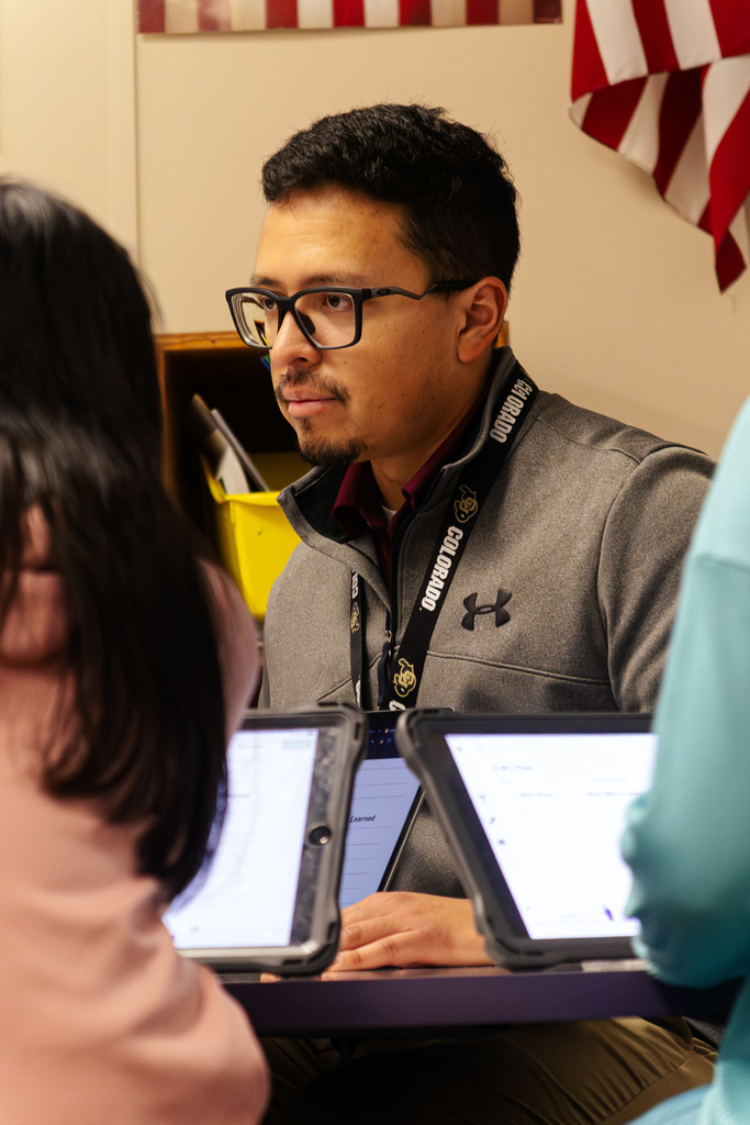 Mr. Ortiz is listening intently to a student during Win time or What I Need time.