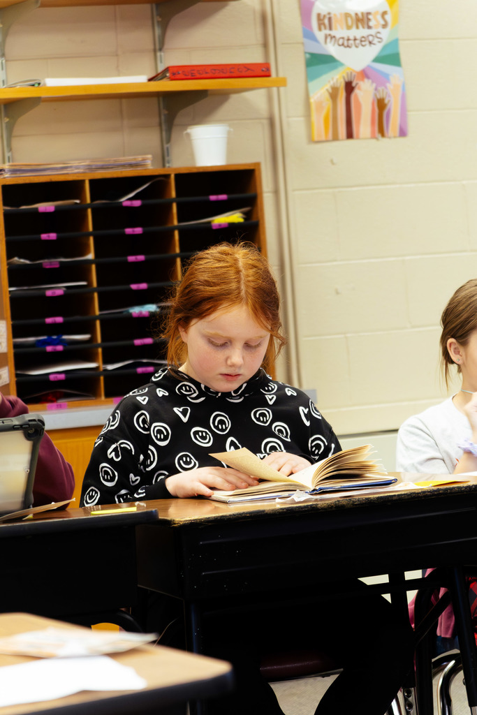 female student reading a book at her desk
